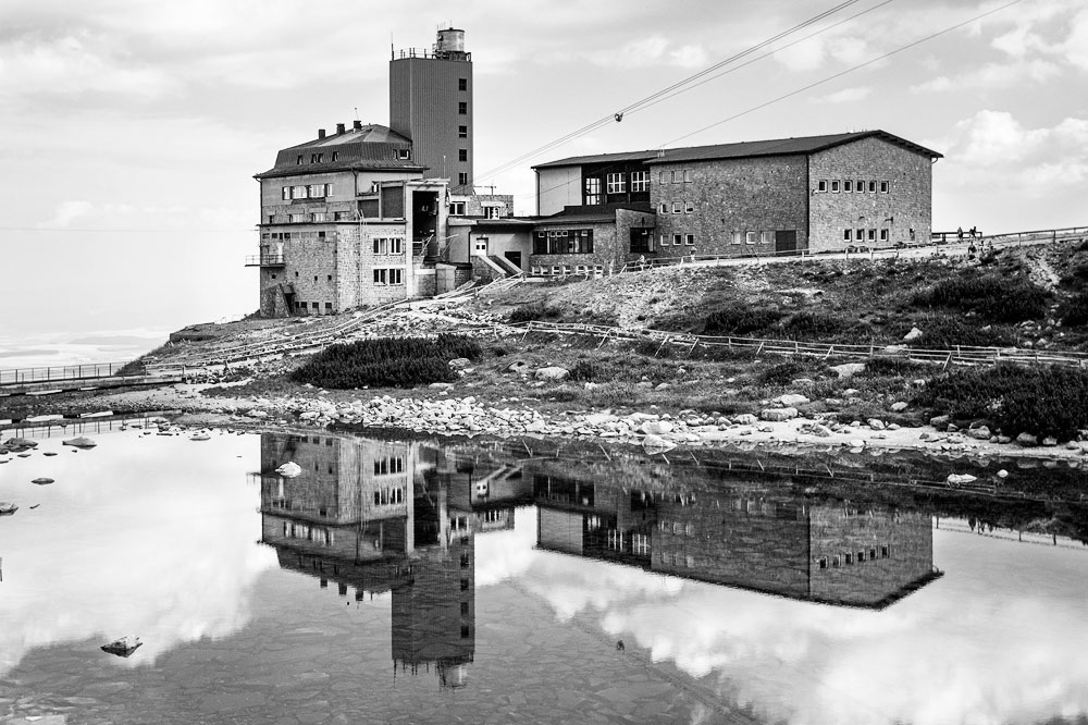 Krajina s budovami a odrazom vo vode — po aplikovaní čiernobieleho presetu